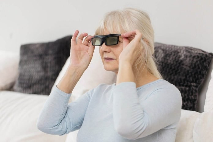 Mature woman wearing smart glasses for a blind person while sitting on a comfortable sofa, adjusting the device as she experiences enhanced vision through advanced technology